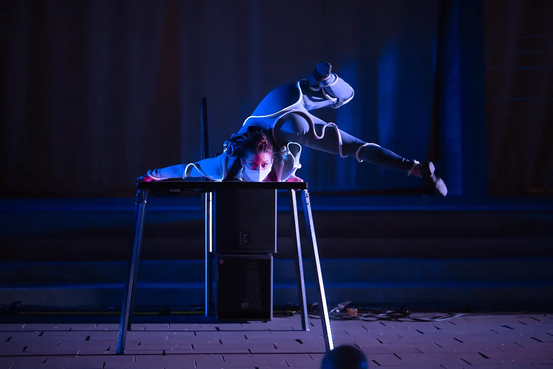 Contortionist balancing on a portable stage table at an outdoor evening show